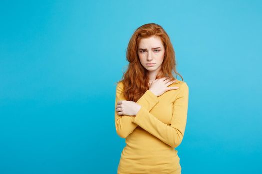 Close up Portrait young beautiful attractive redhair girl feeling nervous looking at camera. Blue Pastel Background. Copy space.