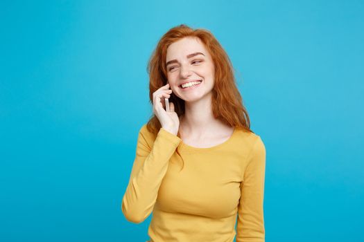 Lifestyle and Technology concept - Portrait of cheerful happy ginger red hair girl with joyful and exciting talking with friend by mobile phone. Isolated on Blue Pastel Background. Copy space.
