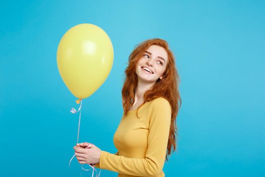 Close up Portrait happy young beautiful attractive redhair girl smiling with colorful party balloon. Blue Pastel Background.