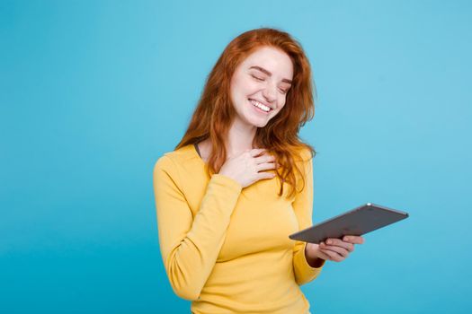 People and Technology Concept - Close up Portrait young beautiful attractive redhair girl happy smiling on digital table with wining something. Blue Pastel Background. Copy space.