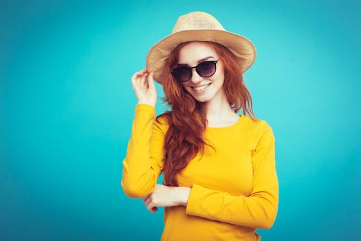 Travel concept - Close up Portrait young beautiful attractive redhair girl wtih trendy hat and sunglass smiling. Blue Pastel Background. Copy space.