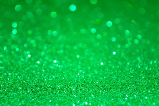Green abstract glitter background with defocused lights bokeh