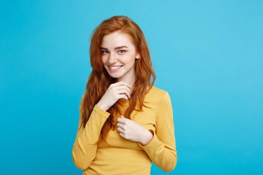 Lifestyle concept - Close up Portrait young beautiful attractive ginger red hair girl playing with her hair with shyness. Blue Pastel Background. Copy space.