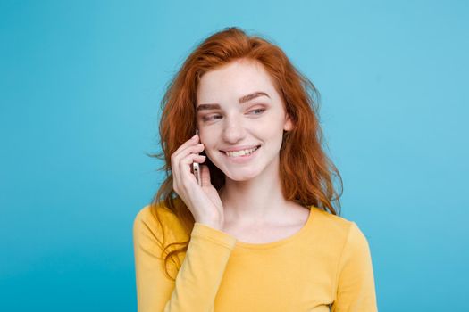 Lifestyle and Technology concept - Portrait of cheerful happy ginger red hair girl with joyful and exciting talking with friend by mobile phone. Isolated on Blue Pastel Background. Copy space.