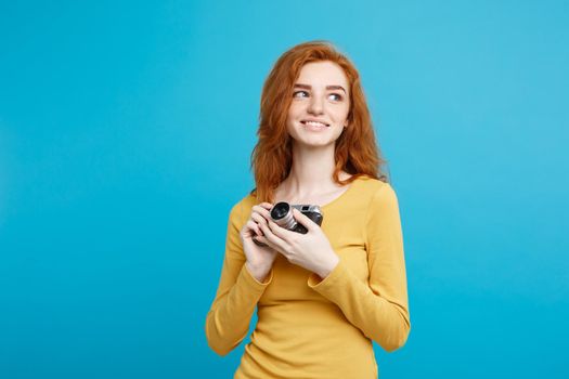 Close up Portrait young beautiful attractive ginger girl happy smiling with vintage camera and ready to travel. Isolated on Blue Pastel Background. Copy space.