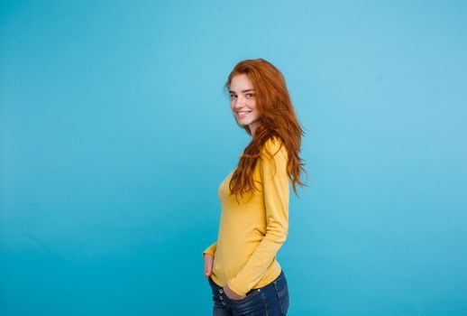 Lifestyle concept - Close up Portrait young beautiful attractive ginger red hair girl playing with her hair with shyness. Blue Pastel Background. Copy space.