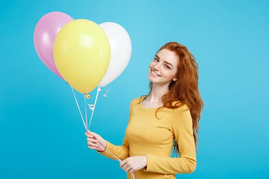 Close up Portrait happy young beautiful attractive redhair girl smiling with colorful party balloon. Blue Pastel Background.