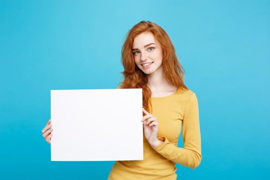 Business Concept - Close up Portrait young beautiful attractive redhair girl smiling showing blank sign. Blue Pastel Background.