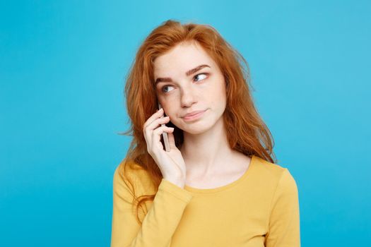 Lifestyle and Technology concept - Portrait of cheerful happy ginger red hair girl with shocking and stressful expression while talking with friend by mobile phone. Isolated on Blue Pastel Background. Copy space.