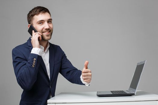 Businessman showing thumbs up while using laptop in office.