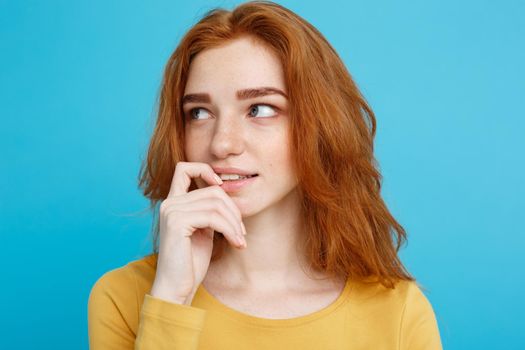 Headshot Portrait of happy ginger red hair girl with freckles smiling looking at camera. Pastel blue background. Copy Space.