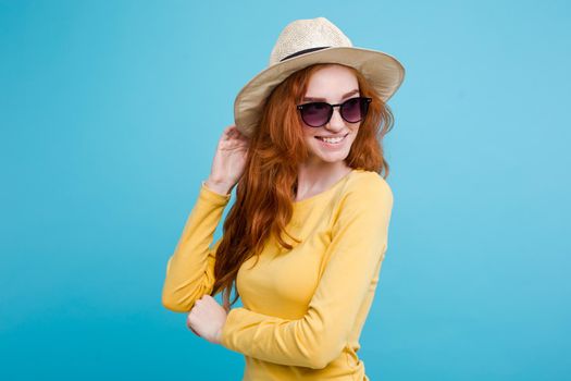 Travel concept - Close up Portrait young beautiful attractive redhair girl wtih trendy hat and sunglass smiling. Blue Pastel Background. Copy space.