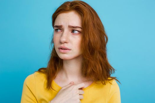 Headshot Portrait of happy ginger red hair girl with freckles smiling looking at camera. Pastel blue background. Copy Space.