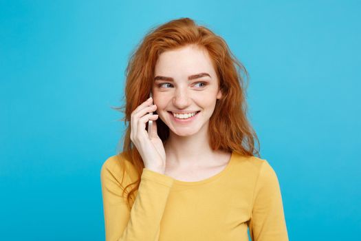 Lifestyle and Technology concept - Portrait of cheerful happy ginger red hair girl with joyful and exciting talking with friend by mobile phone. Isolated on Blue Pastel Background. Copy space.