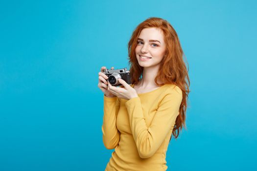 Close up Portrait young beautiful attractive ginger girl happy smiling with vintage camera and ready to travel. Blue Pastel Background. Copy space.