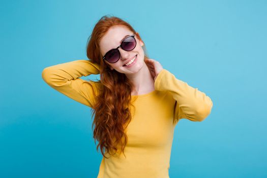 Portrait of happy ginger red hair girl with freckles smiling looking at camera. Pastel blue background. Copy Space.