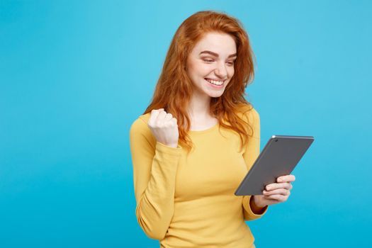 People and Technology Concept - Close up Portrait young beautiful attractive redhair girl happy smiling on digital table with wining something. Blue Pastel Background. Copy space.