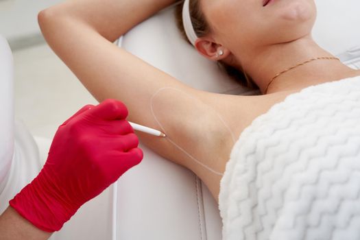 Doctor makes injections of botulinum toxin in the underarm area against hyperhidrosis in beauty salon. Female cosmetology and problems with increased sweating concept