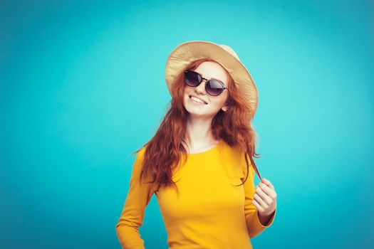 Travel concept - Close up Portrait young beautiful attractive redhair girl wtih trendy hat and sunglass smiling. Blue Pastel Background. Copy space.