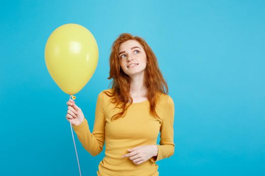 Close up Portrait happy young beautiful attractive redhair girl smiling with colorful party balloon. Blue Pastel Background.