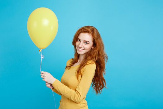 Close up Portrait happy young beautiful attractive redhair girl smiling with colorful party balloon. Blue Pastel Background.