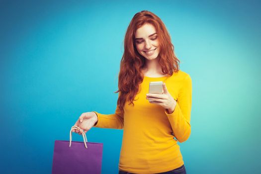 Shopping Concept - Close up Portrait young beautiful attractive redhair girl smiling looking at camera with shopping bag. Blue Pastel Background. Copy space.