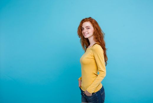 Lifestyle concept - Close up Portrait young beautiful attractive ginger red hair girl playing with her hair with shyness. Blue Pastel Background. Copy space.