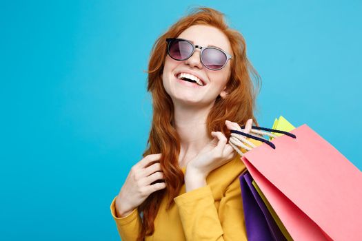 Shopping Concept - Close up Portrait young beautiful attractive redhair girl smiling looking at camera with shopping bag. Blue Pastel Background. Copy space.