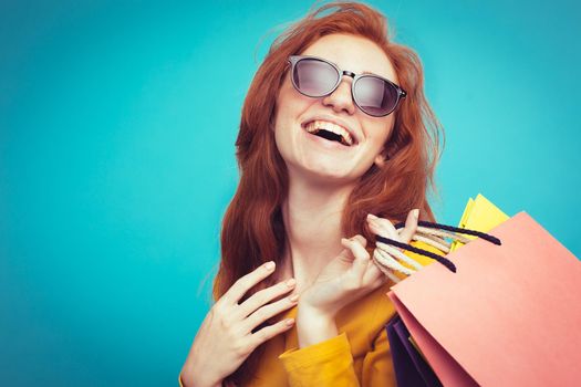 Shopping Concept - Close up Portrait young beautiful attractive redhair girl smiling looking at camera with shopping bag. Blue Pastel Background. Copy space.