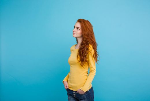 Lifestyle concept - Close up Portrait young beautiful attractive ginger red hair girl playing with her hair with shyness. Blue Pastel Background. Copy space.