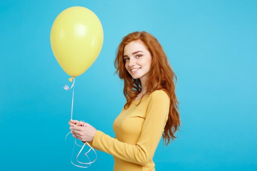 Close up Portrait happy young beautiful attractive redhair girl smiling with colorful party balloon. Blue Pastel Background.