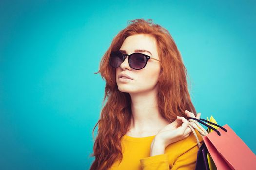 Shopping Concept - Close up Portrait young beautiful attractive redhair girl smiling looking at camera with shopping bag. Blue Pastel Background. Copy space.