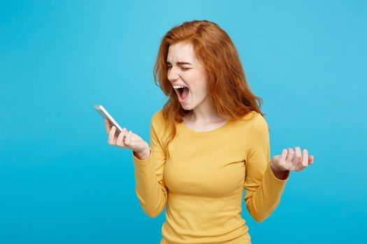 Lifestyle and Technology concept - Portrait of ginger red hair girl shouting on the phone. Isolated on Blue Pastel Background. Copy space.