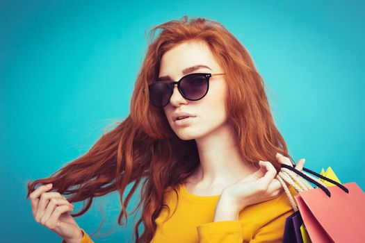 Shopping Concept - Close up Portrait young beautiful attractive redhair girl smiling looking at camera with shopping bag. Blue Pastel Background. Copy space.