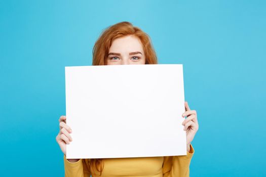 Close up Portrait young beautiful attractive redhair girl smiling showing blank sign. Blue Pastel Background. Copy space.