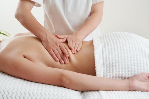 Masseur massaging young woman on massage table in a spa salon. Young woman relaxing during back massage at the spa. Spa treatment concept