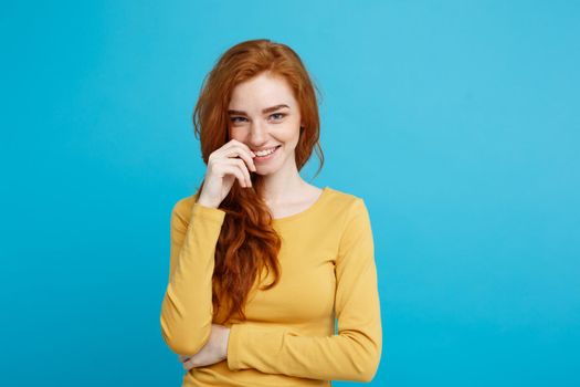 Lifestyle concept - Close up Portrait young beautiful attractive ginger red hair girl playing with her hair with shyness. Blue Pastel Background. Copy space.