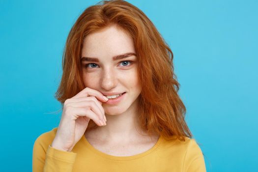 Headshot Portrait of happy ginger red hair girl with freckles smiling looking at camera. Pastel blue background. Copy Space.