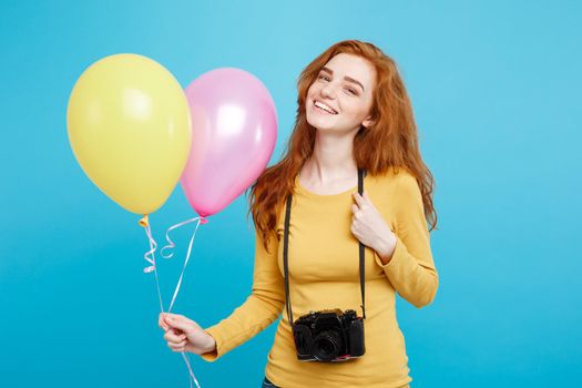 Lifestyle and Party concept - Close up Portrait young beautiful attractive ginger red hair girl with colorful balloon and vintage camera. Blue Pastel Background. Copy space.