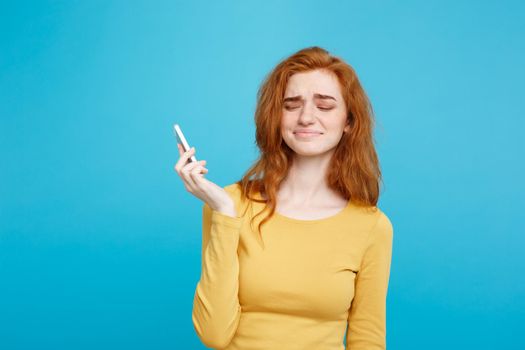 Lifestyle concept - Portrait of a shocked surprised girl in yellow dress talking on mobile phone. Isolated on Blue Pastel Background. Copy space.