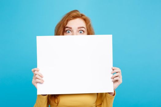 Close up Portrait young beautiful attractive ginger red hair girl smiling showing blank sign. Blue Pastel Background. Copy space.