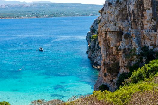 People swimming in the clear blue waters of Proti Island, near Marathopoli, Messinia at Peloponnese. The name of the island derives from the ancient sea god Proteus, son of Poseidon.