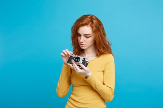 Travel and People Concept - Headshot Portrait of happy ginger red hair girl with playing with vintage camera in happy expression. Pastel blue background. Copy Space.