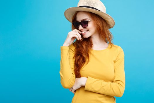 Travel concept - Close up Portrait young beautiful attractive ginger red hair girl with trendy hat and sunglass smiling. Blue Pastel Background. Copy space.