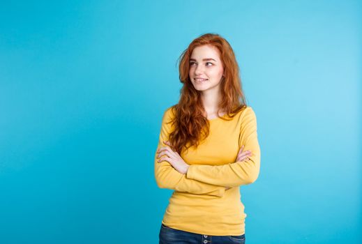 Lifestyle concept - Close up Portrait young beautiful attractive ginger red hair girl playing with her hair with shyness. Blue Pastel Background. Copy space