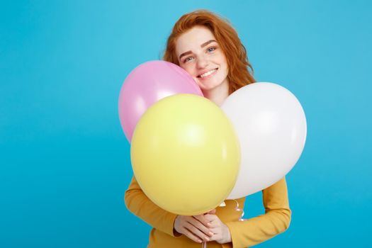 Close up Portrait happy young beautiful attractive redhair girl smiling with colorful party balloon. Blue Pastel Background. Copy space.