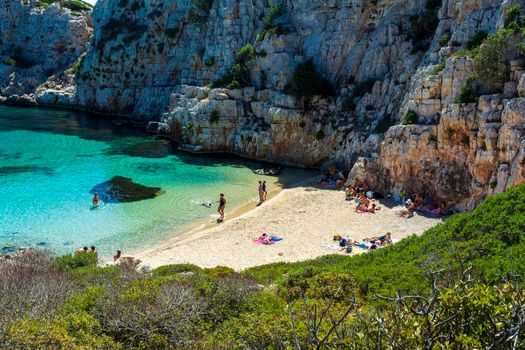 Marathopoli, Greece - August29, 2019: People swimming in the clear blue waters of Proti Island, near Marathopoli, Messinia at Peloponnese. The name of the island derives from the ancient sea god Proteus, son of Poseidon.