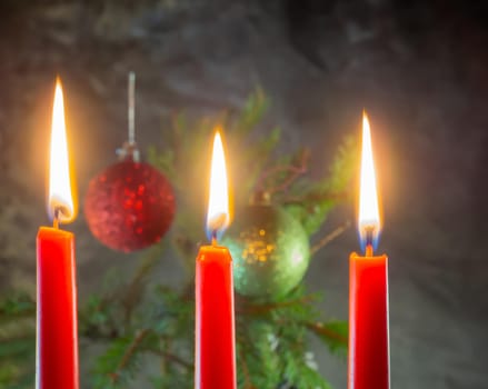 Christmas red candles are burning on the background of fir branches. Christmas decoration. New Year atmosphere
