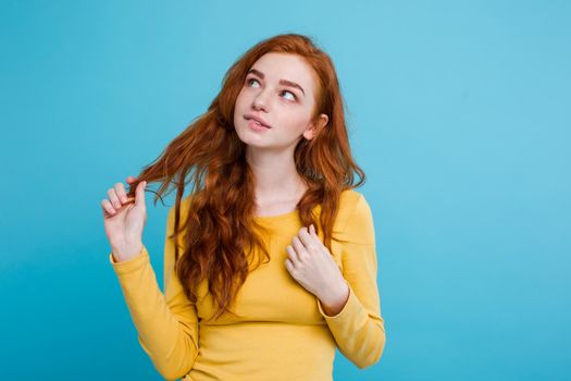 Portrait of happy ginger red hair girl with freckles smiling looking at camera. Pastel blue background. Copy Space.