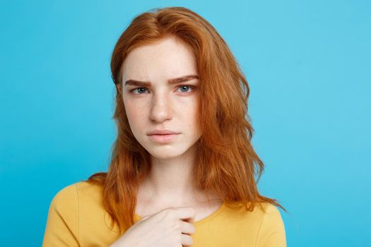 Close up Portrait young beautiful attractive redhair girl feeling nervous looking at camera. Blue Pastel Background. Copy space.